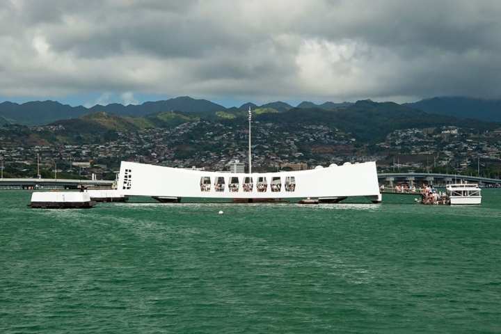 a large ship in a body of water with a mountain in the background