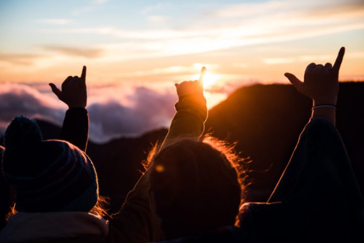 a group of people standing in front of a sunset